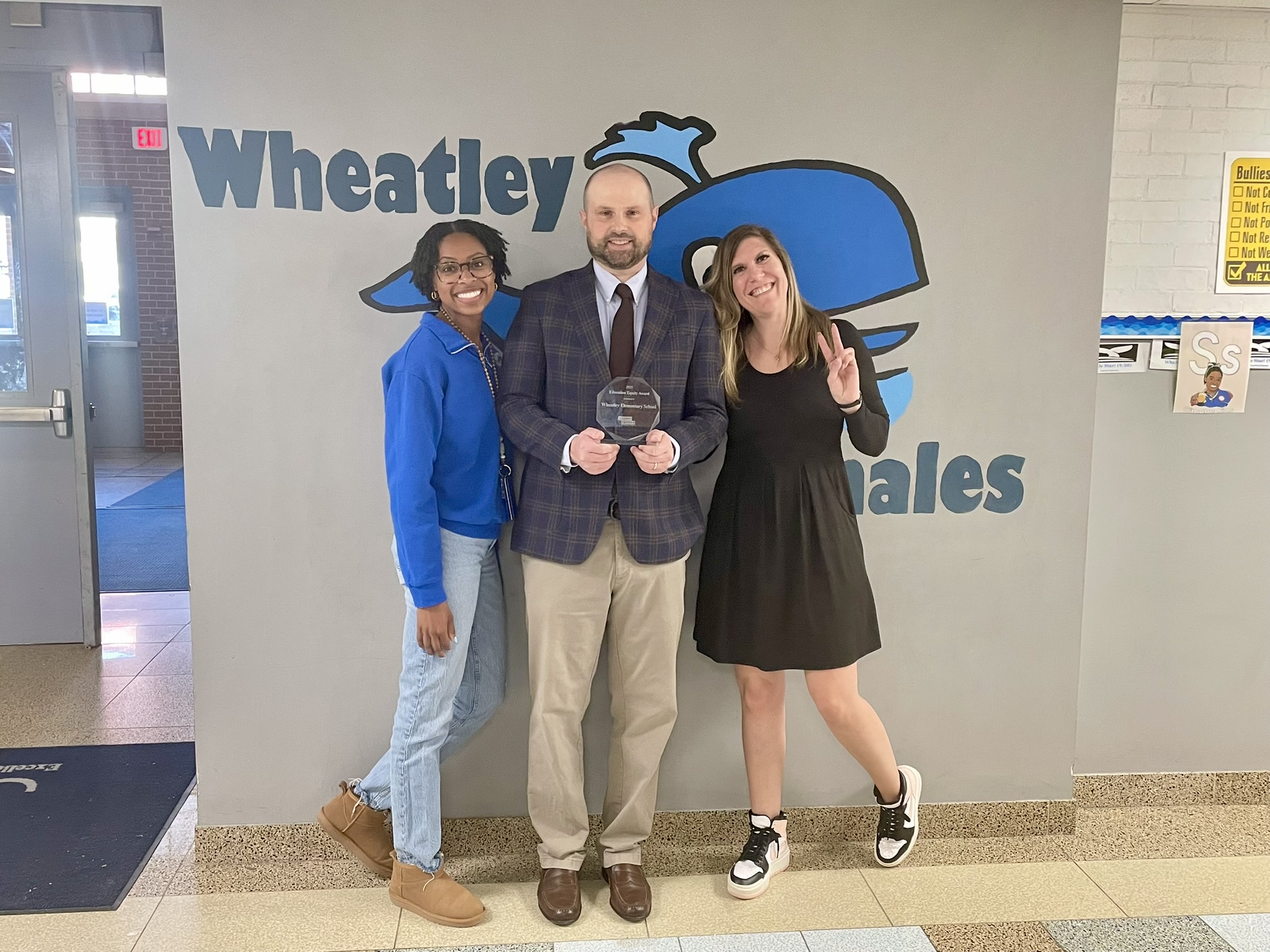 Robert stands between Wheatley Education campus administrators, presenting them with a Ward award.